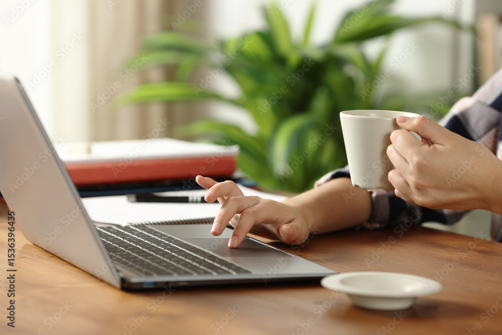 Student hands using laptop drinking coffee on wooden table Student hands using laptop drinking coffee on wooden table