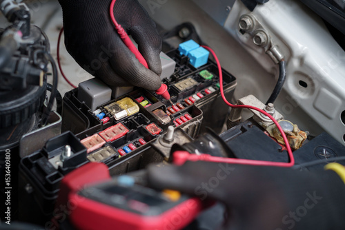 Car Fuse Box Electrical Testing with Multimeter.Technician Checking Automotive Fuses.