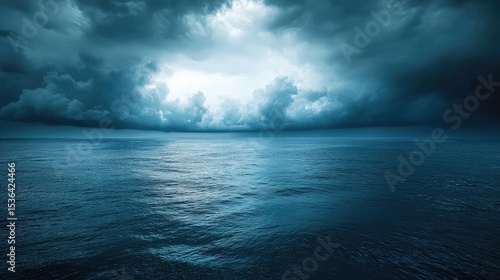 A vast expanse of ocean under a dramatic sky filled with dark clouds and a hint of light breaking through