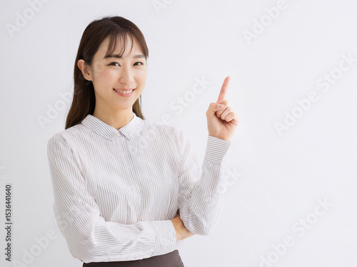 人差し指で上を指す笑顔のビジネス日本人女性