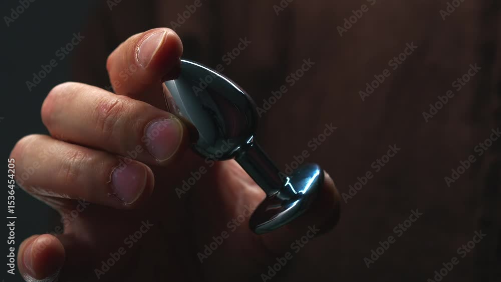 anal toy in hands close-up., Metallic shiny anal plug., Anal sex and  pleasure., Toys for adults., Sex shop and metal dildo