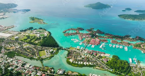 A breathtaking view of Eden Island marina with turquoise water, surrounded by a lush coastline, yachts, and red-roofed residences. Seychelles, Mahe.