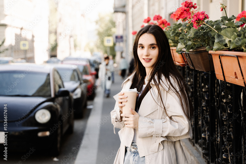 Fototapeta premium Young woman walking with coffee cup on city street in spring