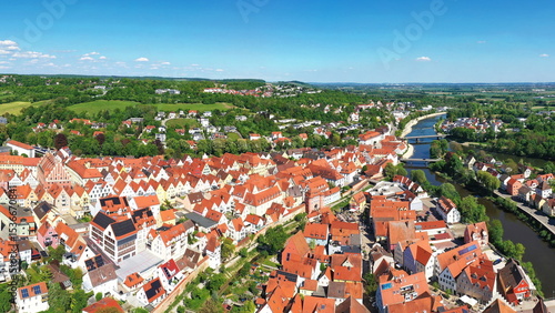 Luftaufnahme von Donauwörth mit roten Dächern, historischen Gebäuden und einem markanten Turm, eingebettet in eine grüne Landschaft. Die Stadt bietet eine charmante Kulisse.