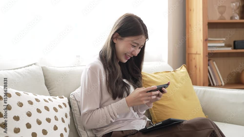 Young woman playing mobile video game with smartphone at home, enjoying technology and online gaming, digital lifestyle, esport, chatting social network, home relaxation entertainment moment Young woman playing mobile video game with smartphone at home, enjoying technology and online gaming, digital lifestyle, esport, chatting social network, home relaxation entertainment moment