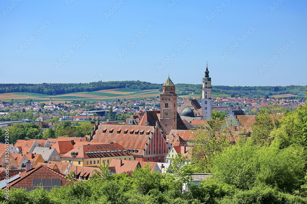 Obraz premium Luftaufnahme von Donauwörth mit roten Dächern, historischen Gebäuden und einem markanten Turm, eingebettet in eine grüne Landschaft. Die Stadt bietet eine charmante Kulisse.