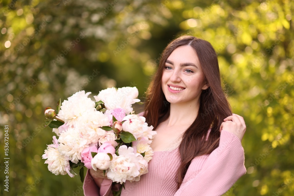 Fototapeta premium Beautiful woman with bouquet of peonies in park