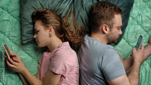 Φωτογραφία Couple Lying Together Yet Apart Focused on Their Smartphones
