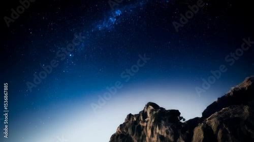 Dramatic low angle of massive rock cliff face under starry night sky showcasing the grandeur of nature and serene celestial beauty.