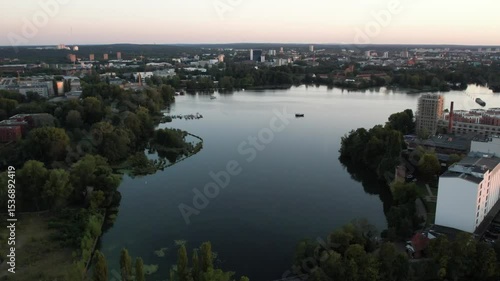 Aerial view of a tranquil lake under a blue sky with distant city buildings on the horizon