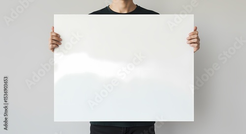 A person holding a blank white poster horizontally, suitable for adding text.