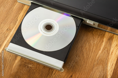 Photo of cd or dvd player with inserted disc on wooden table.