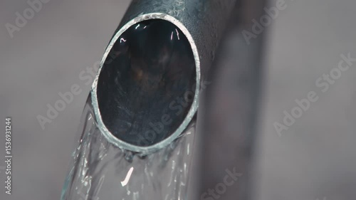 Macro of a metal faucet of a drinking fountain, fresh water pouring 