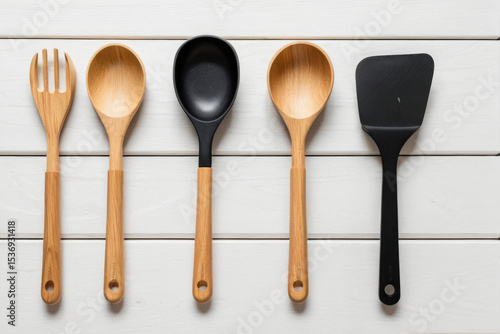 A set of five wooden spoons and one spatula placed neatly on a white table