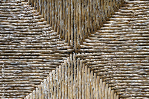 Close-up detail of an old woven reed seat of a chair. The reed here is old and worn
