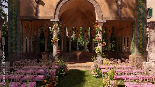 Drone view of Amalfi Coast luxury wedding details: pink chairs, fresh florals, elegant setup at Villa Cimbrone, Ravello. Perfect destination wedding planning vibes see view