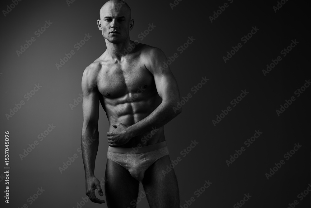 Fototapeta premium Athletic man posing in black and white photography, showcasing toned muscles and confident expression, focusing on strength and grace.