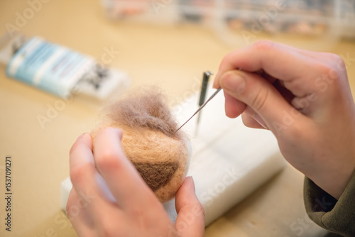 Fototapeta Close-up of artist hands using needle felting technique attaching small piece of
