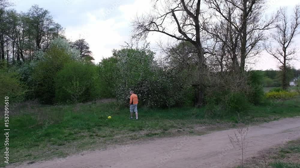 a man in shorts and an orange jacket walks in nature near a lake or river a man in shorts and an orange jacket walks in nature near a lake or river