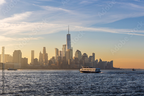 Ferry boat crossing the Hudson River at sunrise with the Financial District, including One World Trade Center, in view.