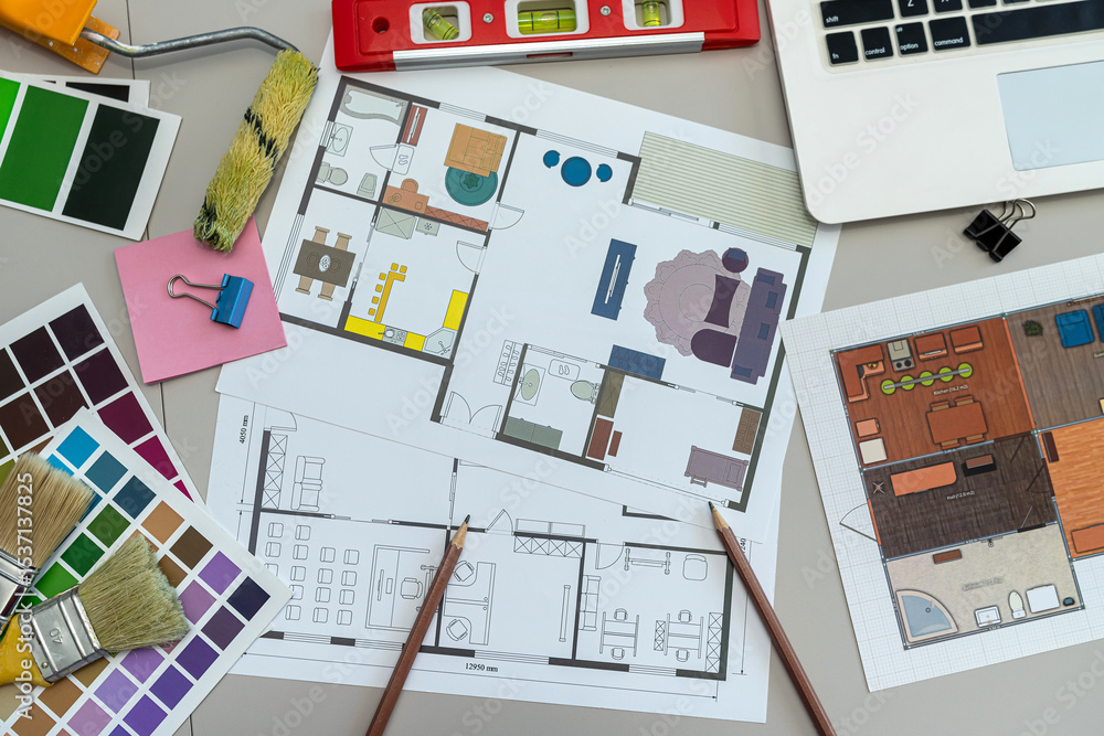 Naklejka premium creative work table with house project, palette of different colors and shades and laptop