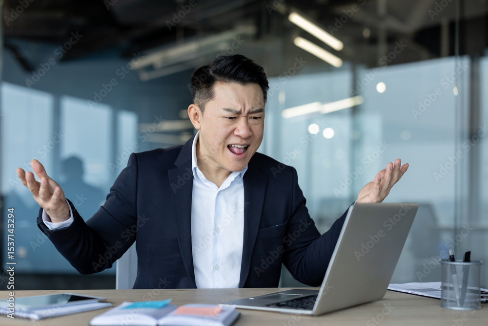 Angry and frustrated young businessman shouting into laptop while talking on online meeting Angry and frustrated young businessman shouting into laptop while talking on online meeting