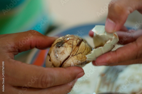 Close up photo of hands peel away a Balut, or fertilized duck egg, before eating it. It is popular street food in the Philippines.
