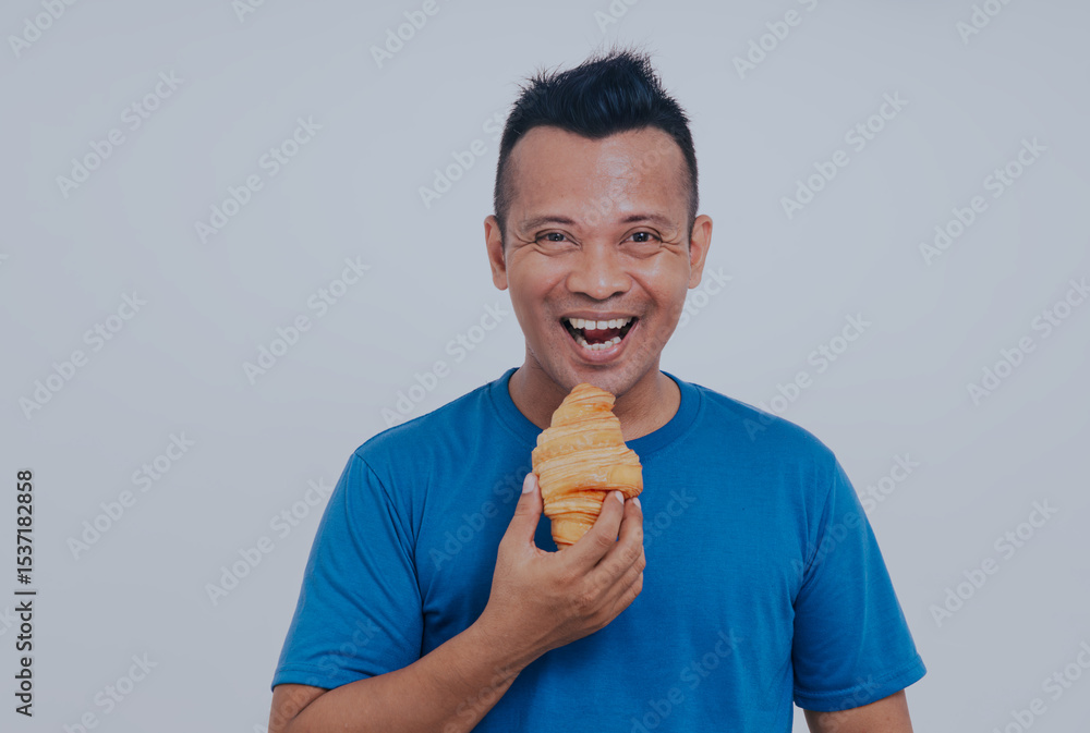 Asian man feeling hungry, enjoying delicious breakfast. Unhealthy but yummy breakfast. Morning tradition concept. Fresh baked croissant. Asian man feeling hungry, enjoying delicious breakfast. Unhealthy but yummy breakfast. Morning tradition concept. Fresh baked croissant.