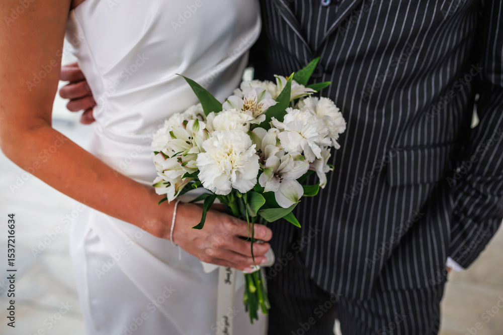 groom embraces the bride with wedding bouquet. rings on the hands of newly-married couple. bride put her hands on the shoulders of the bridegroom. groom embraces the bride with wedding bouquet. rings on the hands of newly-married couple. bride put her hands on the shoulders of the bridegroom.
