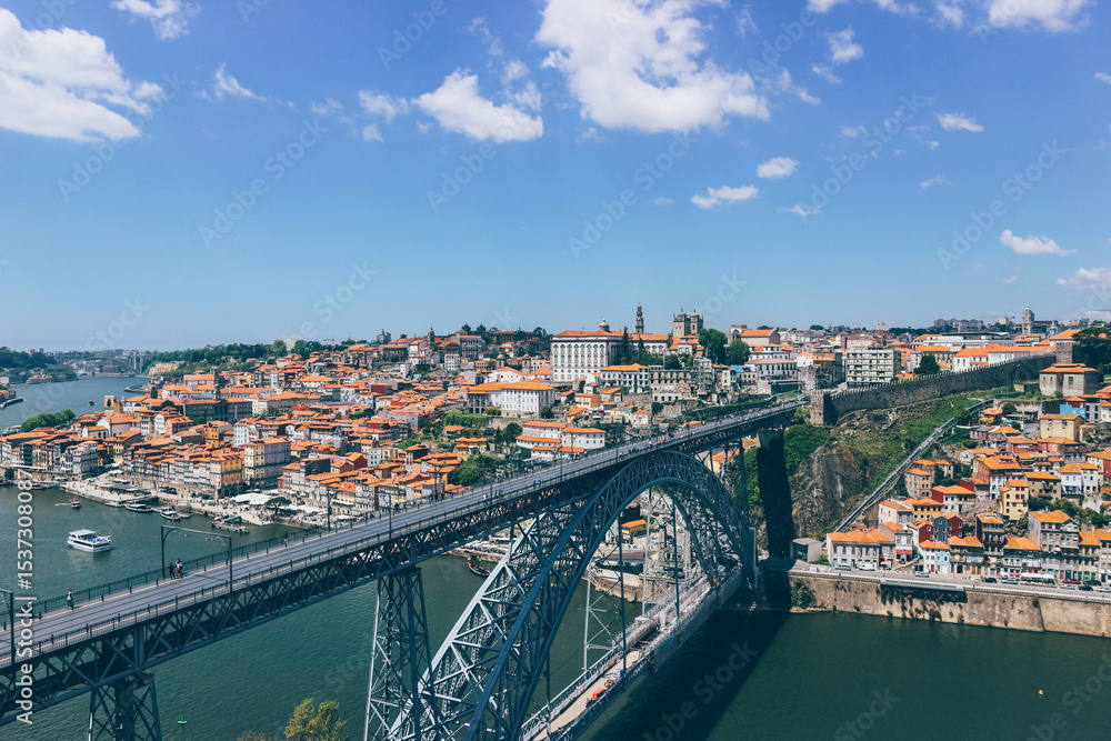 Obraz premium orange rooftops panorama of the old town of porto and duoro river on blue sky day and iron famous eiffel bridge