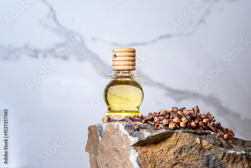 Clove essential oil in a bottle and dry cloves on a rustic wooden background.
