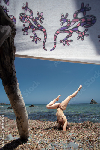 Fit young girl does an inverted balance pose in the Mediterranean Sea on the island of Menorca