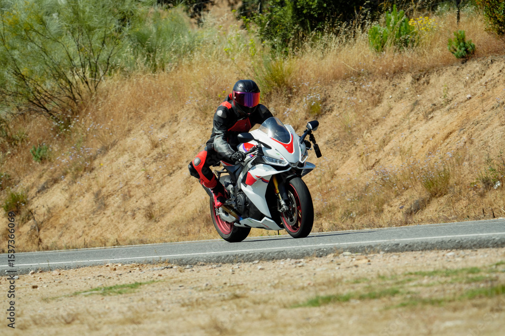 Obraz premium Motorcyclist riding sportbike on country road