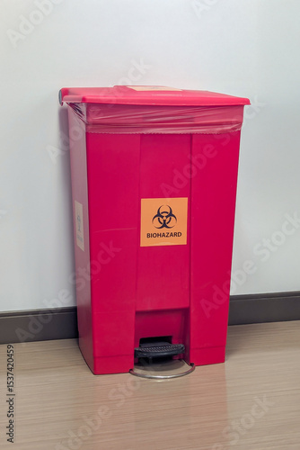 A red biohazard medical waste bin with biohazard symbol
