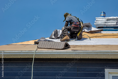 Professional Roofer Installing Asphalt Shingles on Residential House Roof with Safety Equipment