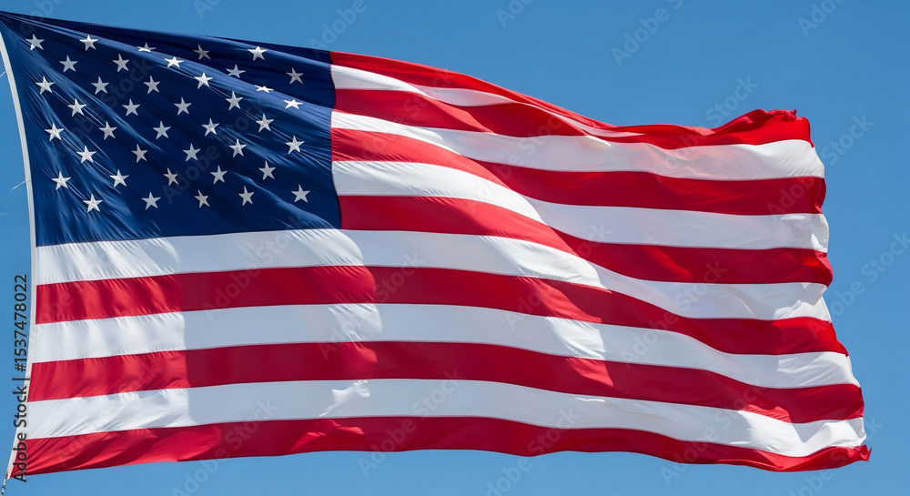 Fototapeta premium Vibrant American flag proudly waving against a clear blue sky, symbolizing freedom, patriotism, and national pride. Perfect for Fourth of July, Memorial Day, election campaigns, or any US-themed