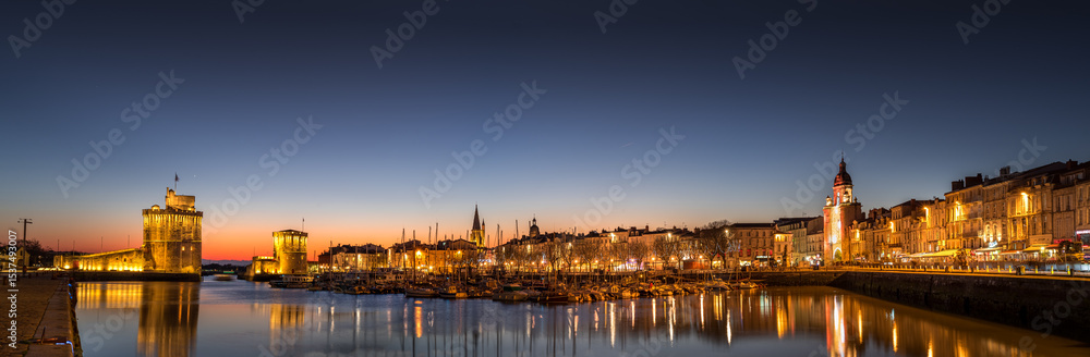Naklejka premium Panoramic view of the old harbour of La Rochelle at sunset. beautiful citylight with reflection on water