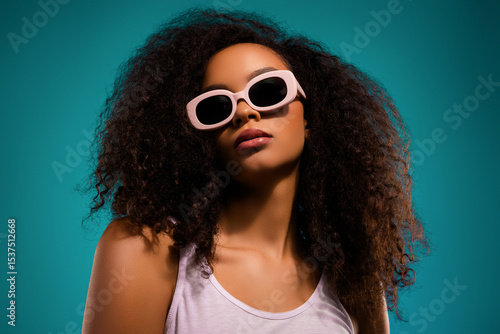 Foto Glamorous young woman posing with sunglass against teal backdrop exuding charm a