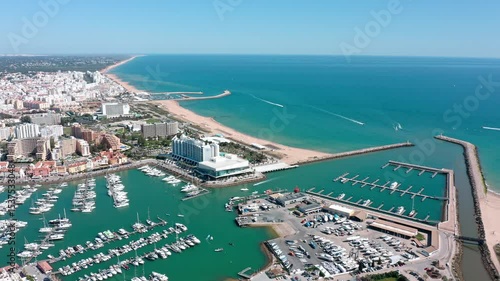 Vilamoura's vibrant marina, filled with yachts and boats, borders a stunning sandy beach, showcasing the beauty of the algarve coastline from an aerial perspective