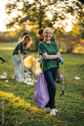 Konstfotografi Senior woman volunteer proudly posing with trash grabber in park cleanup