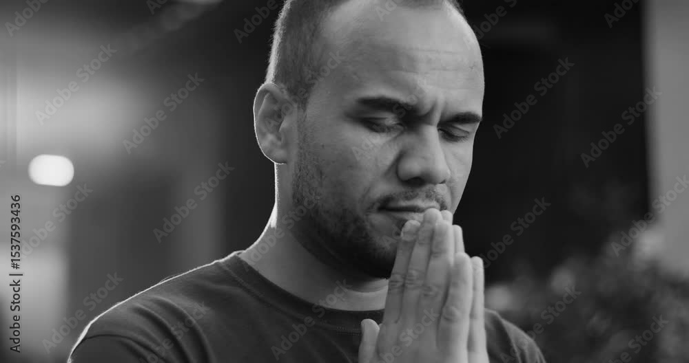 Black and white portrait of Latin American man in prayer with eyes closed and hands pressed together, conveying calm and introspective mood in outdoor setting Black and white portrait of Latin American man in prayer with eyes closed and hands pressed together, conveying calm and introspective mood in outdoor setting