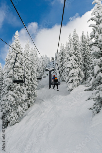 Snowboarder/skier riding a chairlift through the snowy trees at Steamboat Springs ski area in the winter