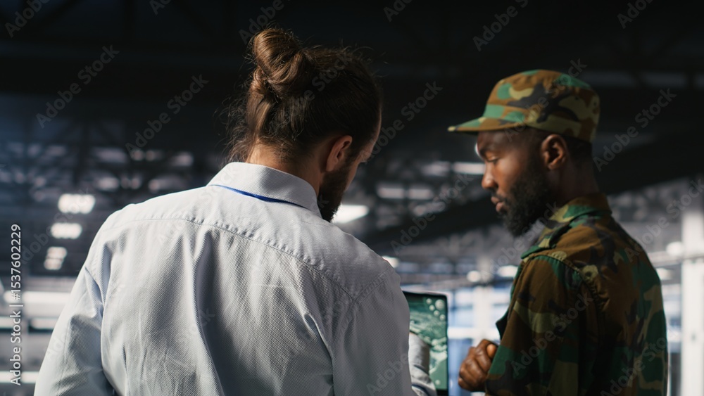 Military technician reviewing tactical dashboard on laptop screen inside secure server hub. Army expert using strategic communications and infrastructure oversight software on notebook Military technician reviewing tactical dashboard on laptop screen inside secure server hub. Army expert using strategic communications and infrastructure oversight software on notebook