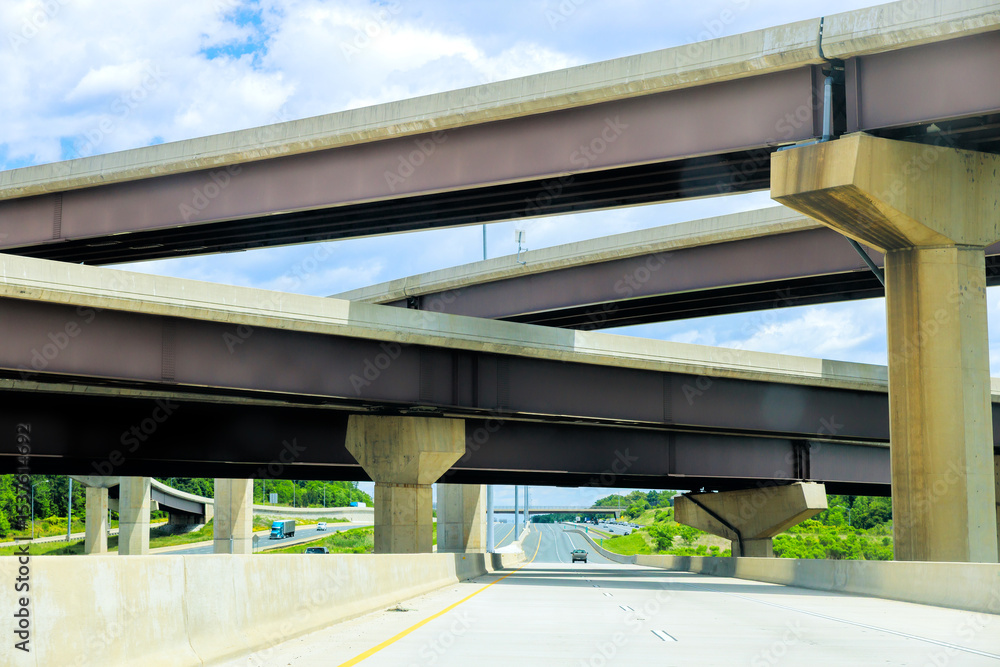 Fototapeta premium Multiple highway overpasses create unique architectural view under with vehicles traveling below.