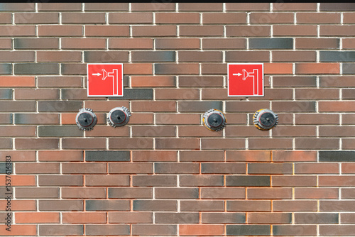 Two fire cranes are mounted on a textured brick wall in a multi-storey building