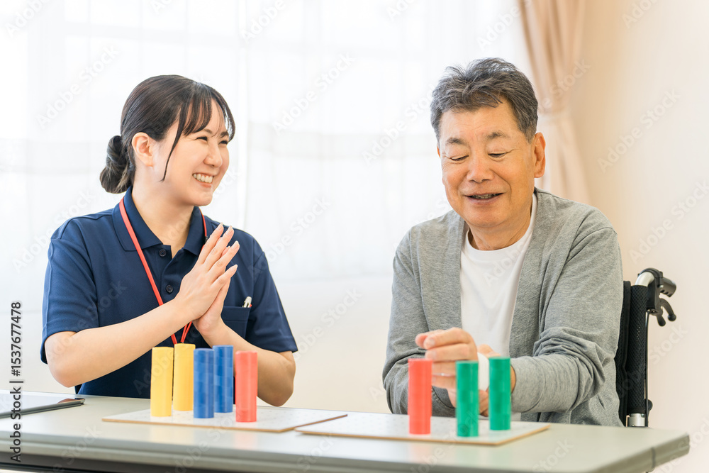 Fototapeta premium 介護施設・リハビリ施設で働く作業療法士の職員とリハビリをするシニア男性 