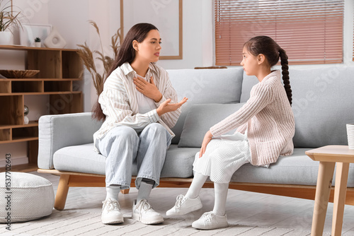 Mother apologizing to her daughter on sofa at home