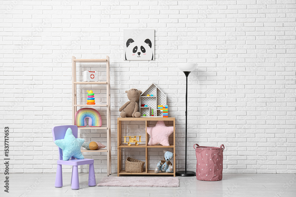 Obraz premium Interior of children's room with many toys in shelving units, chair and lamp near white brick wall
