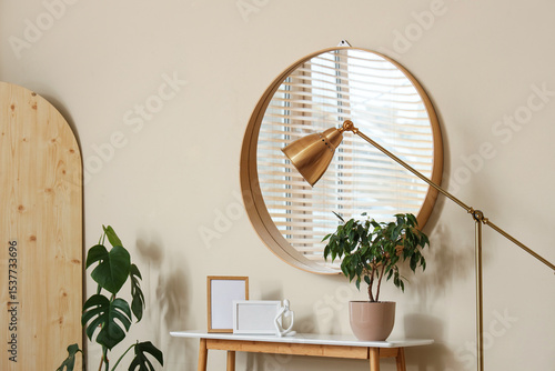 Home decor on table and reflection of stylish window wooden blinds in hanging mirror