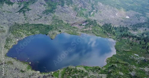 Aerial View of a Lake in the Mountains Surrounded by Green Hills and Rocks. Untouched wilderness